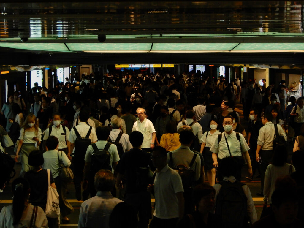 駅構内を行き交う大勢の人々の中で、一人だけこちらを見つめる男性